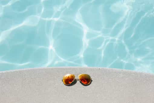 Picture of sunglasses laid by the side of a pool