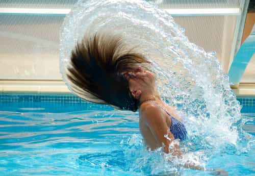 Picture of a woman in a pool swishing her wet hair